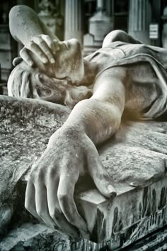 a black and white photo of a statue with hands on it's head laying down