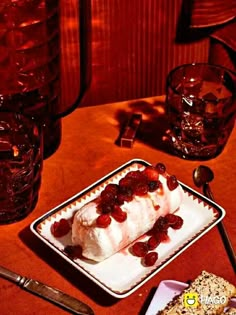 there is a cake with strawberries on it sitting on a plate next to two glasses