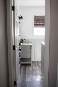 a bathroom with white walls and wood floors