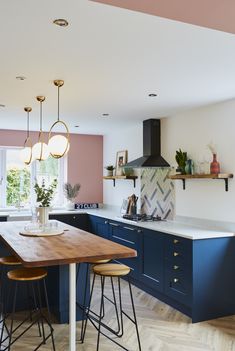 a kitchen with blue cabinets and counter tops, wooden flooring and two pendant lights hanging from the ceiling