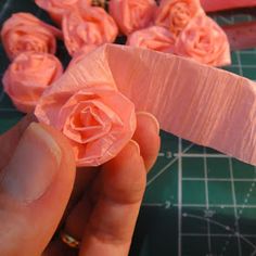 a person holding a piece of pink paper with flowers on it next to some scissors