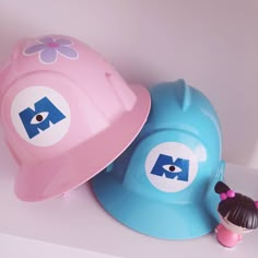 two children's helmets sitting next to each other on top of a white shelf