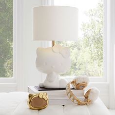 a white lamp sitting on top of a bed next to a pair of gold rings