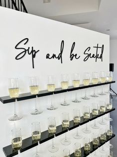 there are many wine glasses lined up on the shelf in front of the sign that says sip and b'est saut