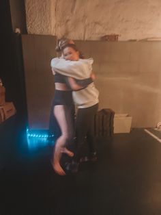 two people hugging each other while standing in front of a wall with lights on it