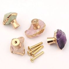 four different types of knobs and handles on a white surface with gold hardware, including an amethyst