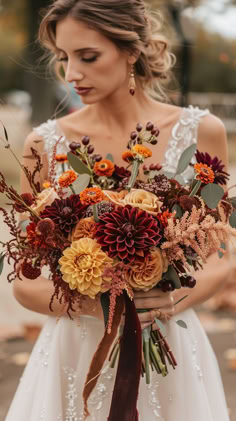 a woman in a wedding dress holding a large bouquet with orange and yellow flowers on it