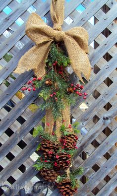 a christmas tree made out of pine cones and burlocks is hanging on a fence