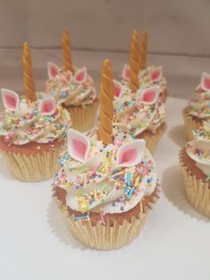 several cupcakes with unicorn ears and sprinkles on them are arranged in rows