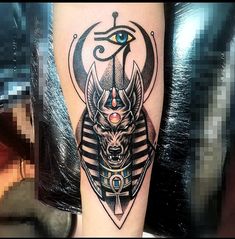 an egyptian tattoo on the leg of a person with a demon head and eye in it