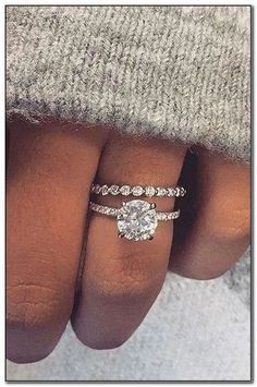 a woman's hand with two engagement rings on it and the ring is in between her fingers