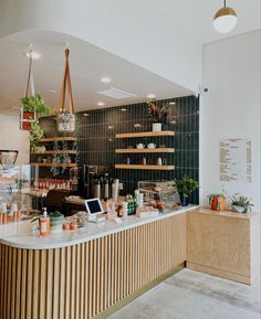 a counter in a restaurant with lots of food on it and plants hanging from the ceiling