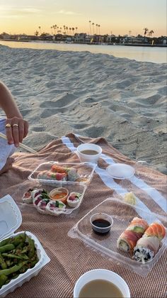 a woman sitting on the beach eating sushi