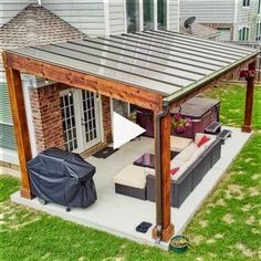 a covered patio with couches and table in the middle of grass next to a house