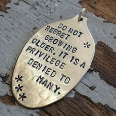 a silver pendant with words on it that says do not repeat growing older it is a pril