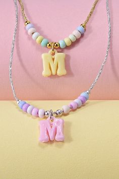 two necklaces with the letter m on them, one is pink and one is blue