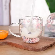 a glass cup filled with milk sitting on top of a wooden cutting board next to an orange