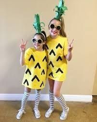 two girls dressed up as pineapples posing for the camera with their hands in the air