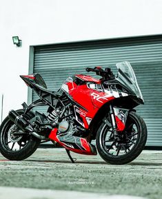 a red and black motorcycle parked in front of a garage