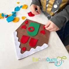 a young boy is making a gingerbread cake with icing and felt decorations on the table