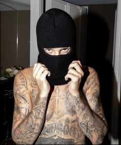 a tattooed man wearing a black mask covering his face