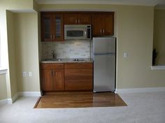 an empty kitchen with wooden cabinets and stainless steel refrigerator freezer in the middle of the room