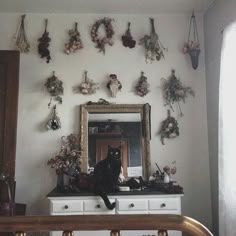 a black cat sitting on top of a dresser next to a mirror