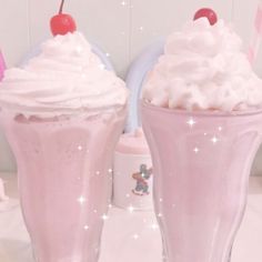 two ice cream sundaes with cherries and whipped cream in them on a table