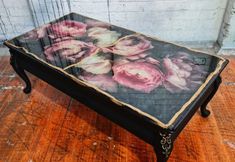 a coffee table with flowers painted on the top and bottom, sitting on a wooden floor