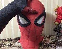 a spider - man mask is being held up by someone's arm and head