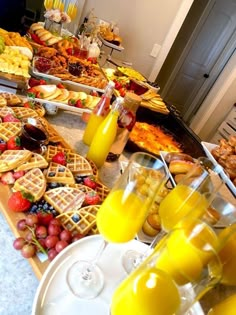 a table filled with lots of different types of food and glasses of orange juice in front of them