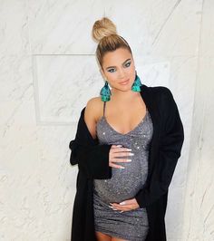 a woman in a silver dress and black jacket posing with her arms on her hips