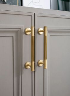 a close up of a door handle on a cabinet with a clock in the background