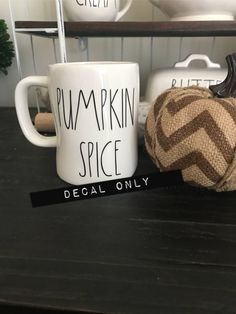 two coffee mugs with the words pumpkin spice on them sitting next to a burluck