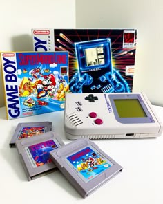 an old nintendo gameboy sitting on top of a table next to two video games