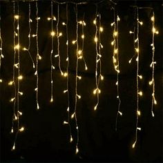 some lights that are hanging from the side of a black wall in front of a window