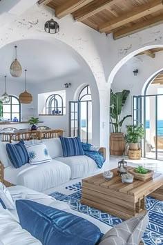 a living room filled with white furniture and lots of blue pillows on top of it