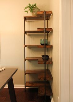 a wooden shelf sitting in the corner of a room next to a table with a potted plant on it