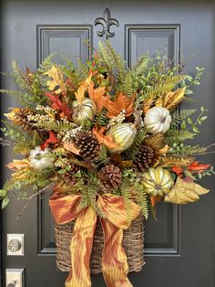 a basket filled with lots of fall leaves and flowers sitting on top of a door