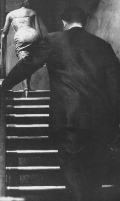 an old photo of a man and woman walking up the stairs in black and white