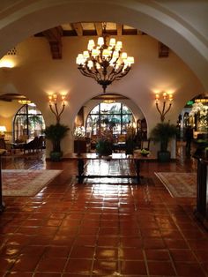 the inside of a hotel lobby with chandeliers hanging from the ceiling and tiled floors