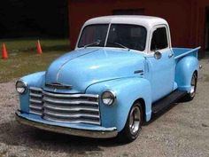 an old blue truck parked in front of a building