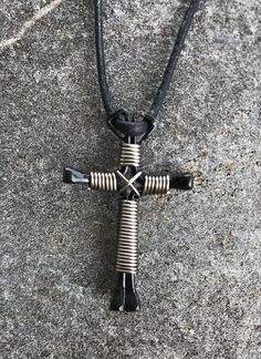 a cross made out of wire and leather cord on the ground with no one around it