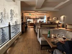 people sitting at tables in a restaurant with wallpaper on the walls and wood flooring