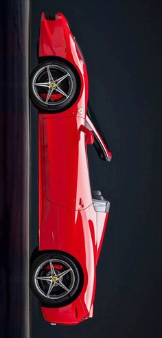 a red sports car hanging upside down on a pole in front of a black background