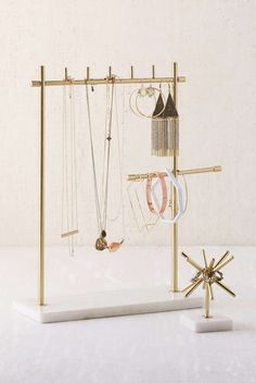 a gold jewelry rack with multiple necklaces and rings hanging from it's sides