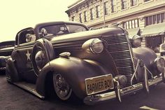 an antique car is parked on the side of the road in front of other old cars