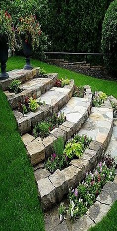 an outdoor garden with stone steps and flowers in the center, surrounded by green grass