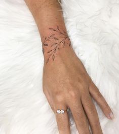 a woman's hand with a leaf tattoo on her left wrist and diamond ring