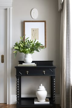 a potted plant sitting on top of a black table next to a white vase